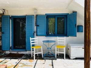 two chairs and a table in front of a house with blue shutters at Aloni Petit House in Nerotriviá