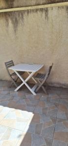 a white table and two chairs next to a wall at Maisonette bedogao in Valence