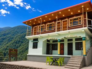 a house with a table and chairs in front of it at Harshil Pinewood Homestay in Harsil +22 photos