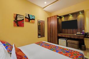 a bedroom with a bed and a flat screen tv at FabHotel Pride - Electronic City in Bangalore