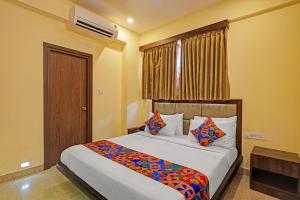 a bedroom with a large bed with colorful pillows at FabHotel Pride - Electronic City in Bangalore