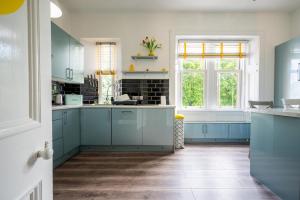a kitchen with blue cabinets and a window at Culzean Road, Retreat in Maybole