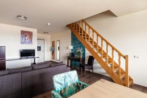 a living room with a couch and a staircase at Hotel Gerardushoeve in Heijenrath