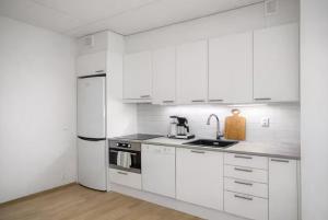 a white kitchen with white appliances and white cabinets at Modern studio next to Finnoo metro - Tuohi BossHomes in Espoo