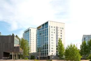 a tall white office building with glass windows at Modern studio next to Finnoo metro - Tuohi BossHomes in Espoo