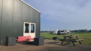 a building with a couch and a picnic table next to a table at Studio Rozenbottel shared bathroom in Hensbroek