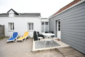 a patio with a table and chairs next to a building at Gîte Maison de pêcheur in Le Crotoy