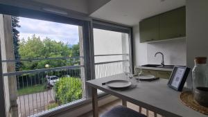 a kitchen with a table and a large window at Studio moderne Climatisé Meylan centre proche CHU in Meylan