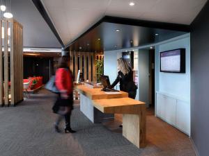 a woman standing at a desk with a laptop at ibis Caen Porte De Bretagne in Bretteville-sur-Odon