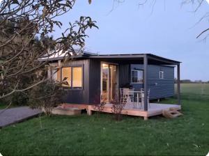 a tiny house with a deck in a field at Farmstay in Elingamite North +6 photos