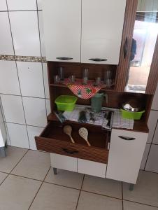 a kitchen cabinet with some bowls and utensils at cantinho do descanso in Dourados +4 photos