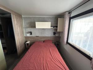 a bed in a room with a red blanket at Camping du CONGUEL in Quiberon