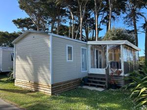 a small house in the grass with a porch at Camping du CONGUEL in Quiberon