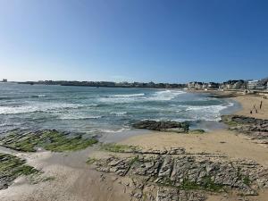 a beach with rocks and the ocean on a sunny day at Camping du CONGUEL in Quiberon +1 photo