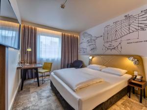 a hotel room with a large bed and a desk at Mercure Hotel Berlin City in Berlin