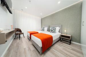 a bedroom with a large bed with an orange blanket at Guesthouse Solar do Mar in Silveira