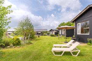 a yard with two lounge chairs and an umbrella at Tiny House XL | 2 persons in Gasselte
