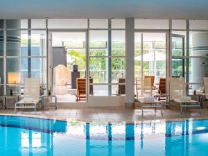 a hotel lobby with a pool and chairs at PULLMAN Stuttgart Fontana in Stuttgart