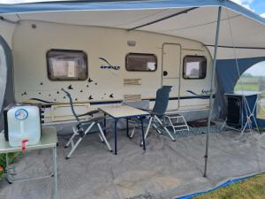 a tent with a table and chairs in front of it at Falsterly Glamping in Horbelöv