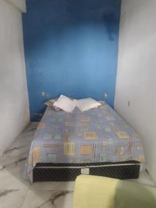 a bed in a room with a blue wall at Chalé de família in Mangaratiba