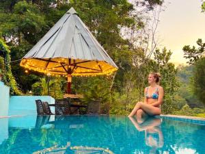 a woman sitting on the edge of a swimming pool at Misty valley Private Pool Villa Munnar in Anachal
