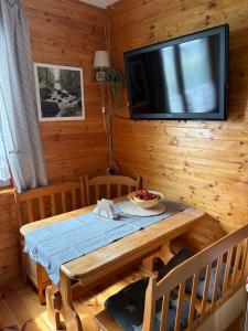 a dining room with a table and a flat screen tv at Amaleczka Woda Las in Podjazdy