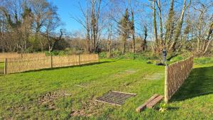 a garden with a fence and a grate in the grass at Camping La Ferme du Guéric in Riec-sur-Bélon