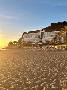 a hotel on the beach with chairs on the sand at Fish & Banana Beach House in Taurito