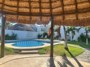 a swimming pool with a straw umbrella and a resort at La Casa del Cenote in Playa del Carmen