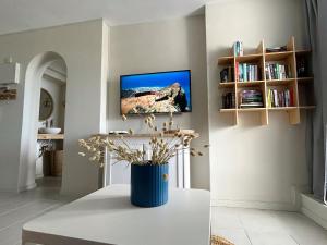 a living room with a table and a tv on the wall at Fish & Banana Beach House in Taurito