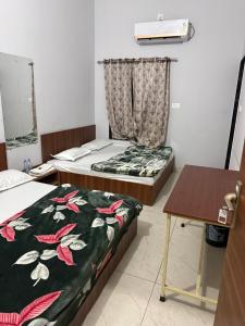 a room with two beds and a table and a desk at RADHA DEVI GUEST HOUSe in Juliāsar