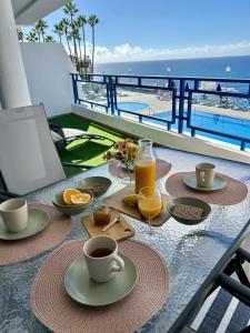 a table with a breakfast of coffee and orange juice at Fish & Banana Beach House in Taurito