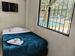 a room with a bed with a towel and a window at Hotel campestre terrazas y sol in La Vega