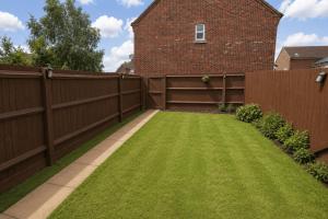 a backyard with a fence and green grass at 4-Bedroom Family Home in Mickleover - Private Driveway - Spacious Garden in Derby