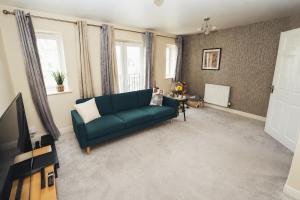 a living room with a blue couch and a tv at 4-Bedroom Family Home in Mickleover - Private Driveway - Spacious Garden in Derby