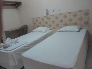 two beds in a room with white sheets and pillows at Dom Manuel Hotel in Abaetetuba
