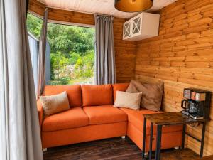an orange couch in a room with a window at Wisla66 Domki nad Wisłą Piotrawin in Piotrawin