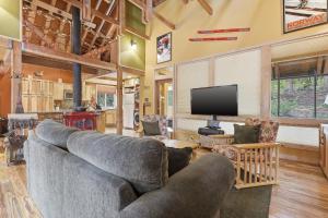 a living room with a couch and a flat screen tv at A-Frame Home with Deck & BBQ - VH223 cabin in Bear Valley