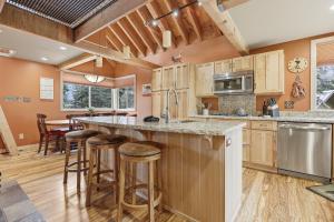 a kitchen with wooden cabinets and a large island with bar stools at A-Frame Home with Deck & BBQ - VH223 cabin in Bear Valley +31 photos