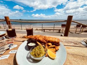 a plate of food on a table next to the beach at Rothsay Beach House in Newbiggin-by-the-Sea