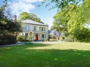 a white house with a red door and a yard at Oak Lodge - Uk49400 in Pembrokeshire
