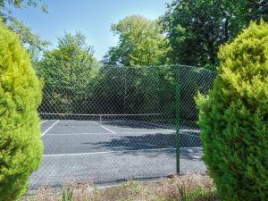 a tennis court behind a fence with trees at Oak Lodge - Uk49400 in Pembrokeshire