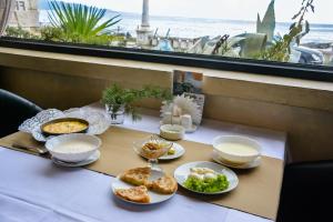 een tafel met borden met voedsel erop met uitzicht op de oceaan bij DEM Hotel in Soechoemi