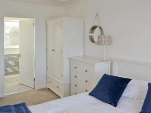 ein Schlafzimmer mit einem weißen Bett und einem blauen Kissen in der Unterkunft Craster View in Craster