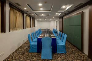 a conference room with a long table and blue chairs at La Woods Hotel in Chennai