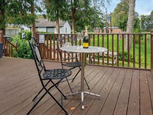 a table and two chairs with a bottle of wine at Glenbeagles Lodge in Dollar