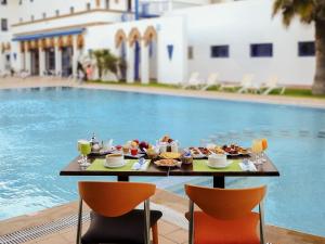 a table with breakfast food next to a swimming pool at Ibis El Jadida in El Jadida