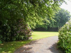 a gravel road in a park with trees and flowers at The Garden Lodge Flat - Uk49415 in Pembrokeshire