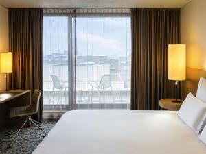 a hotel room with a large bed and a large window at Pullman Basel Europe in Basel