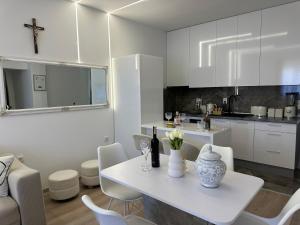 a white kitchen with a table and white chairs at Novi apartman Posušje in Posušje